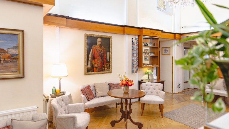 Elegante Hotel-Lobby mit Gem&auml;lde, Sitzgruppe und Blumen auf Tisch.