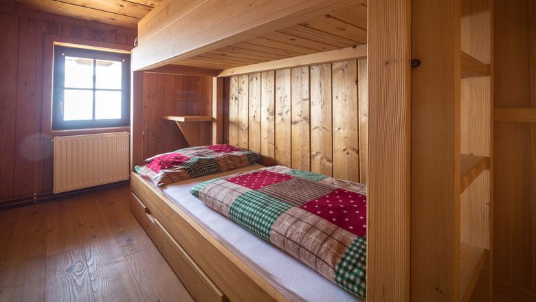 Holzvertäfeltes Zimmer mit Etagenbett und karierten Decken.
