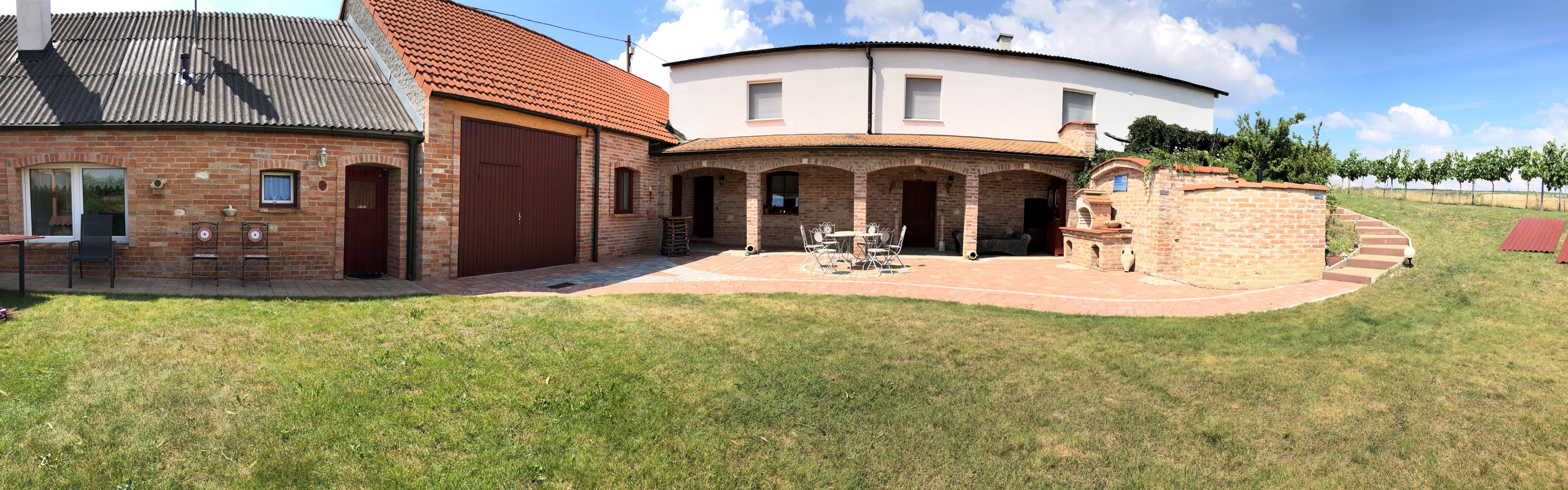 Backsteinbau mit Garten und Terrasse bei sonnigem Wetter.