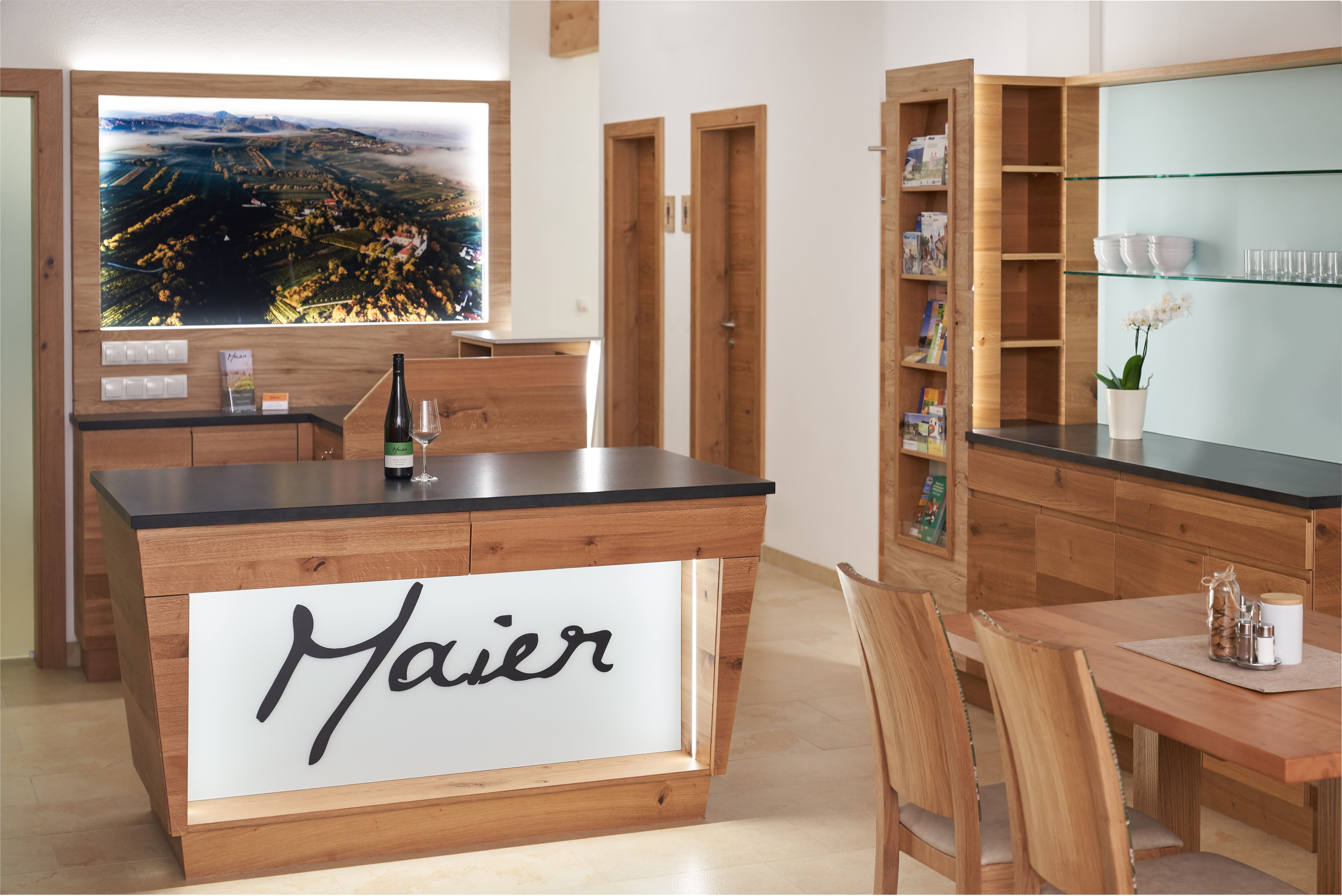 Innenansicht eines modernen Empfangsbereichs mit Holzmöbeln und einem großen Landschaftsbild an der Wand.