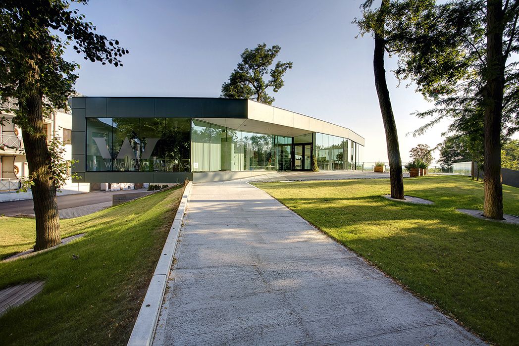 Moderne Glasfassade der Gebietsvinothek Weritas in Kirchberg am Wagram, umgeben von Bäumen und gepflegtem Rasen.