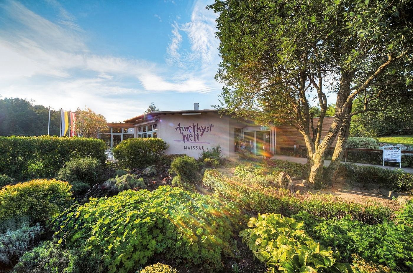 Eingang zur Amethyst Welt Maissau mit Garten und Bäumen im Vordergrund.