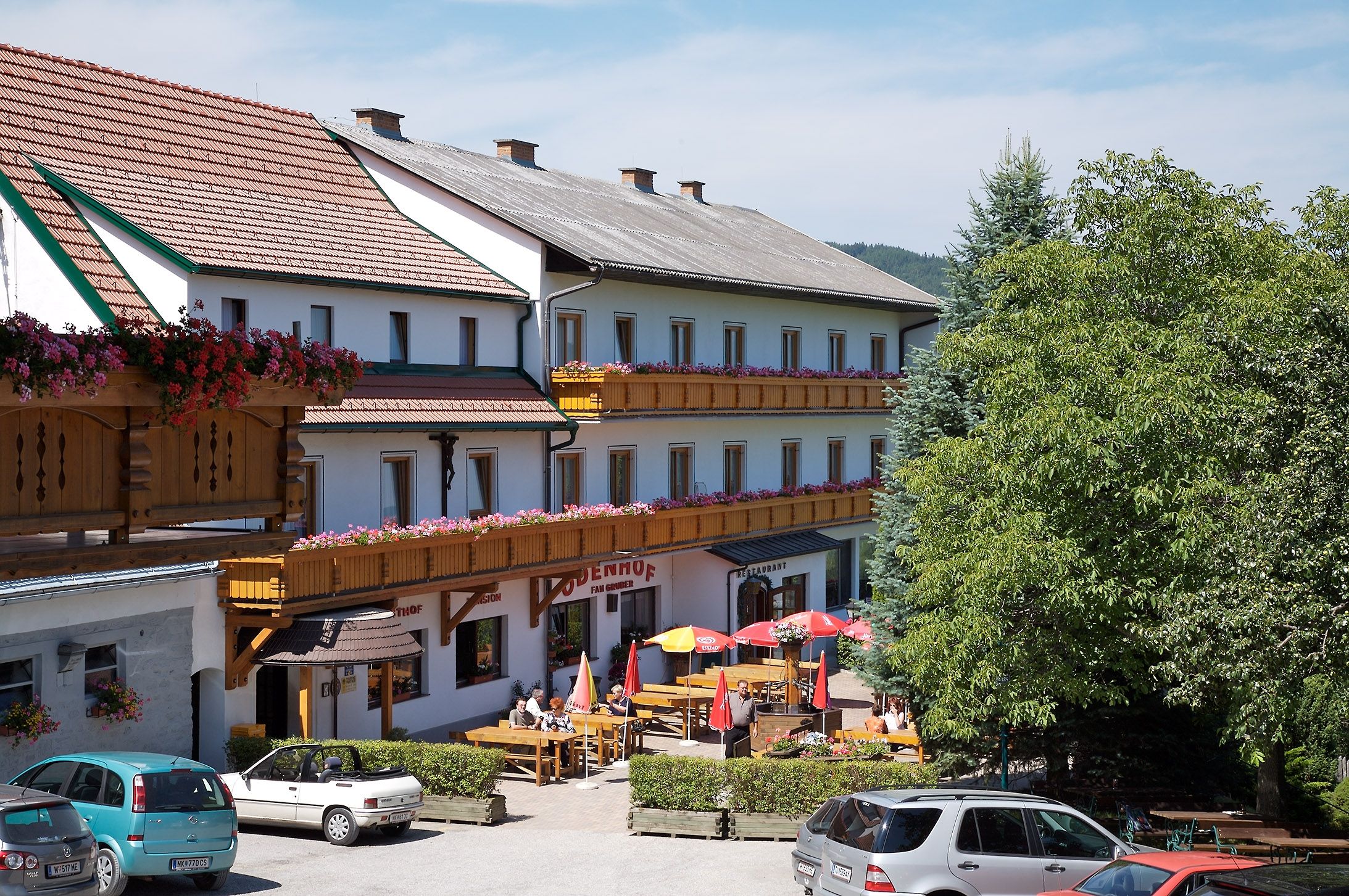Gasthof-Pension Ödenhof mit Terrasse und geparkten Autos.