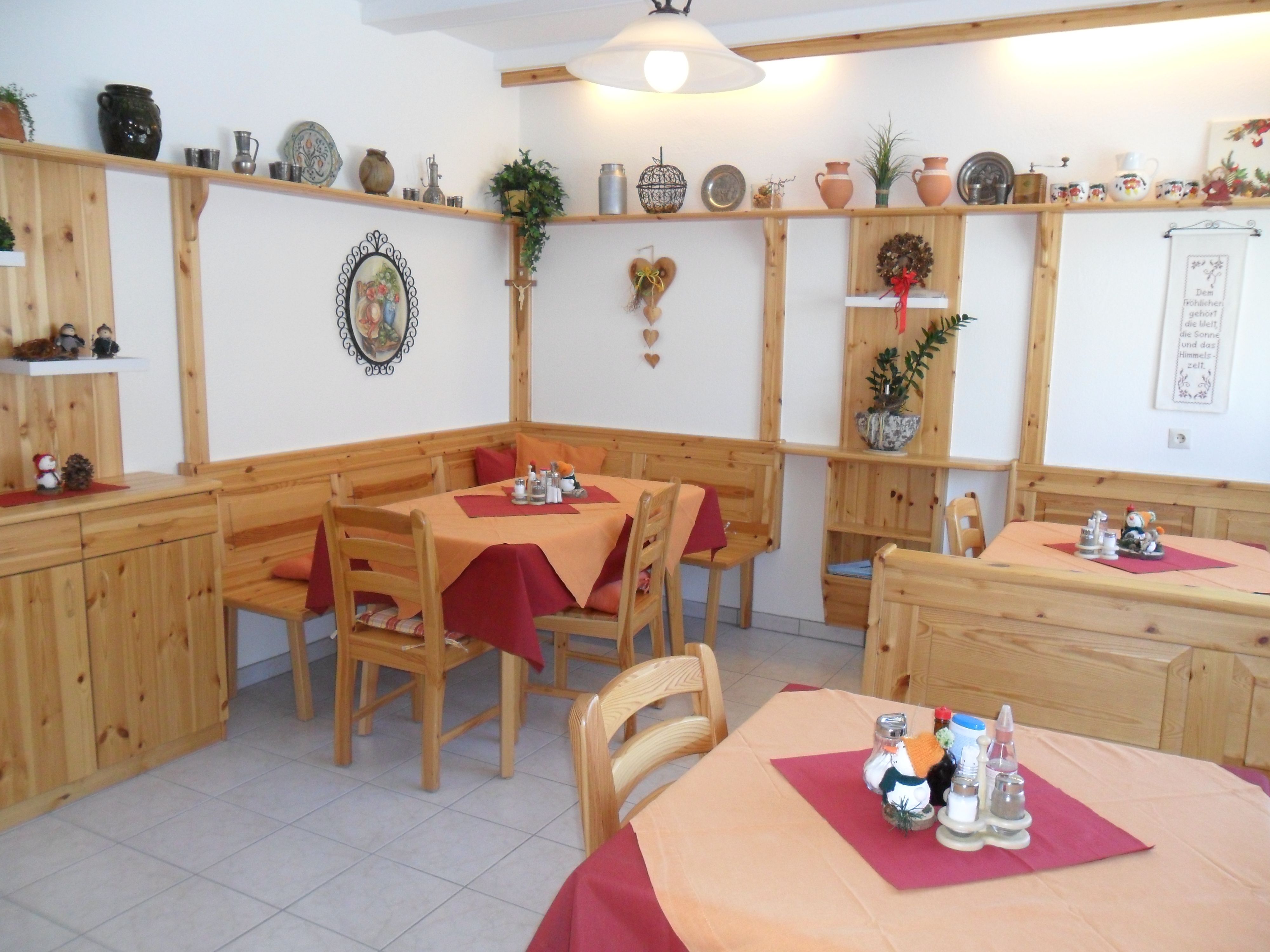 Gemütlicher Frühstücksraum mit Holzmöbeln und Dekorationen an den Wänden.