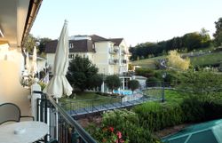 Ein Hotel inmitten einer grünen Landschaft mit Teich und Liegestühlen.