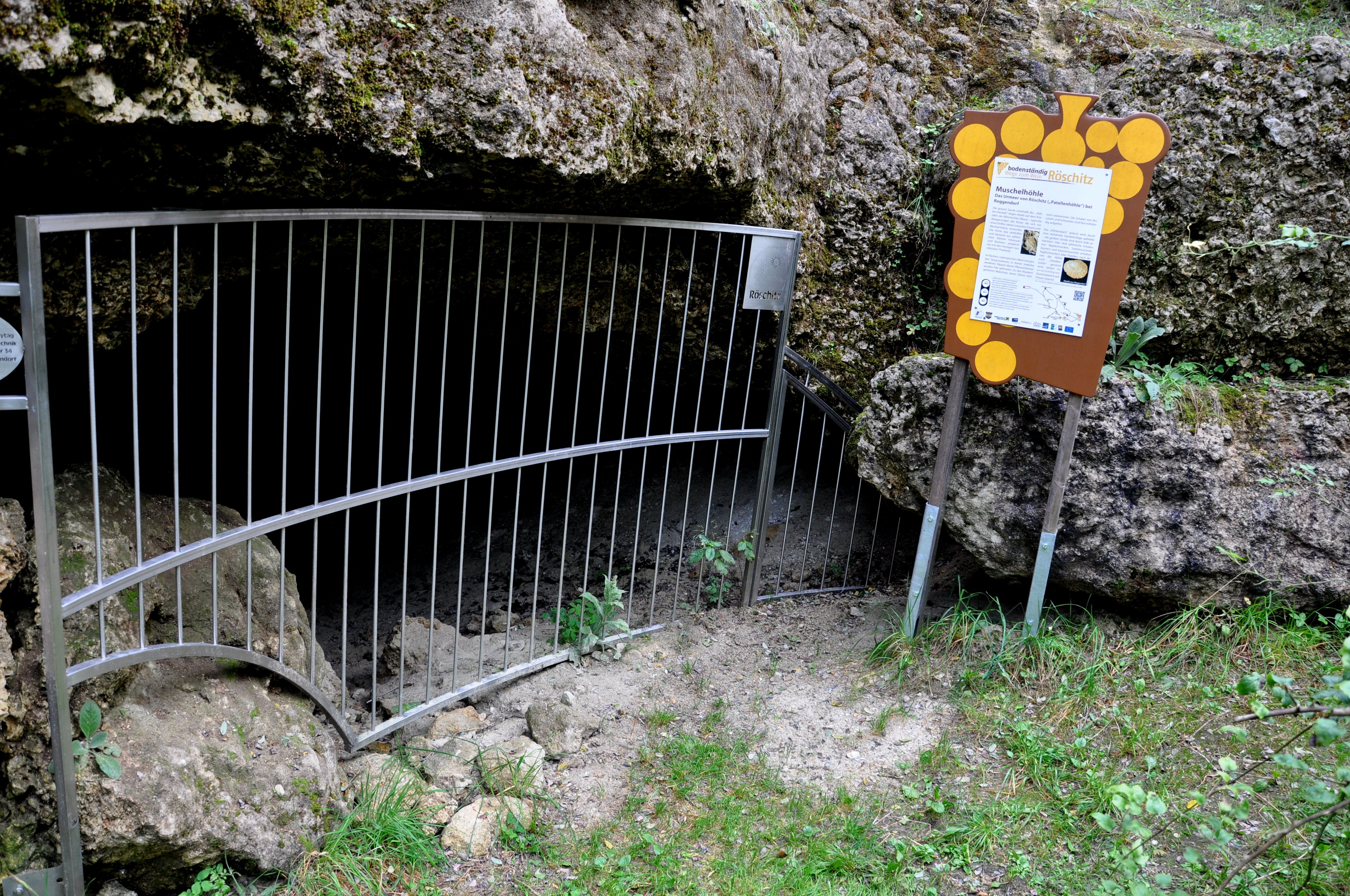 Eingang zur Muschelhöhle Röschitz mit Gitter und Infotafel.