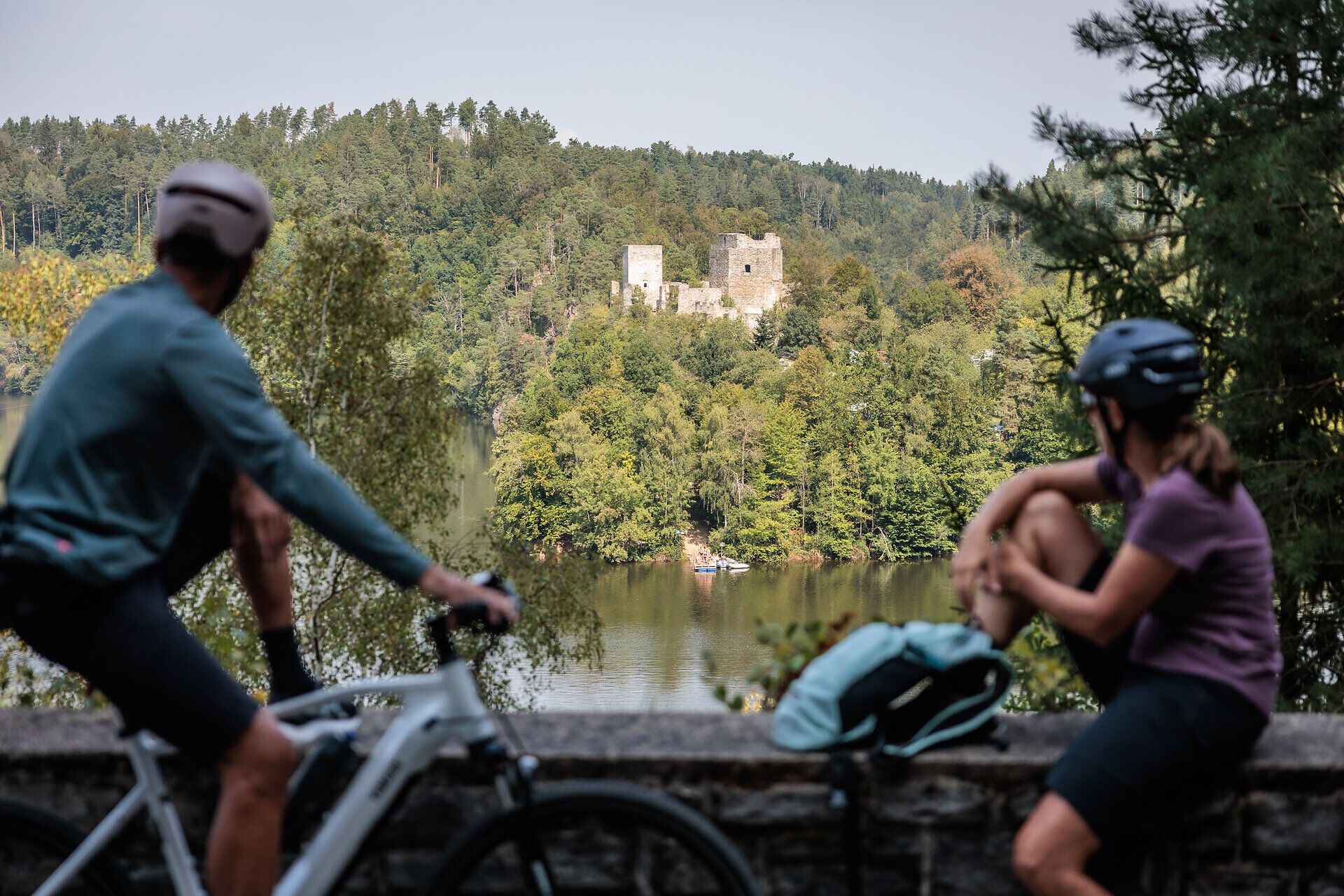 Die sanften Hügel um den Stausee Dobra laden zu einer entspannenden Pause ein. Radfahrer genießen die malerische Aussicht auf die beeindruckende Ruine, während die Natur in voller Blüte steht und die sanften Wellen des Wassers leise plätschern.