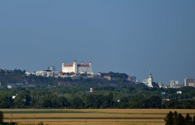 Blick auf die Burg Bratislava und die Stadt im Hintergrund, umgeben von grüner Landschaft.