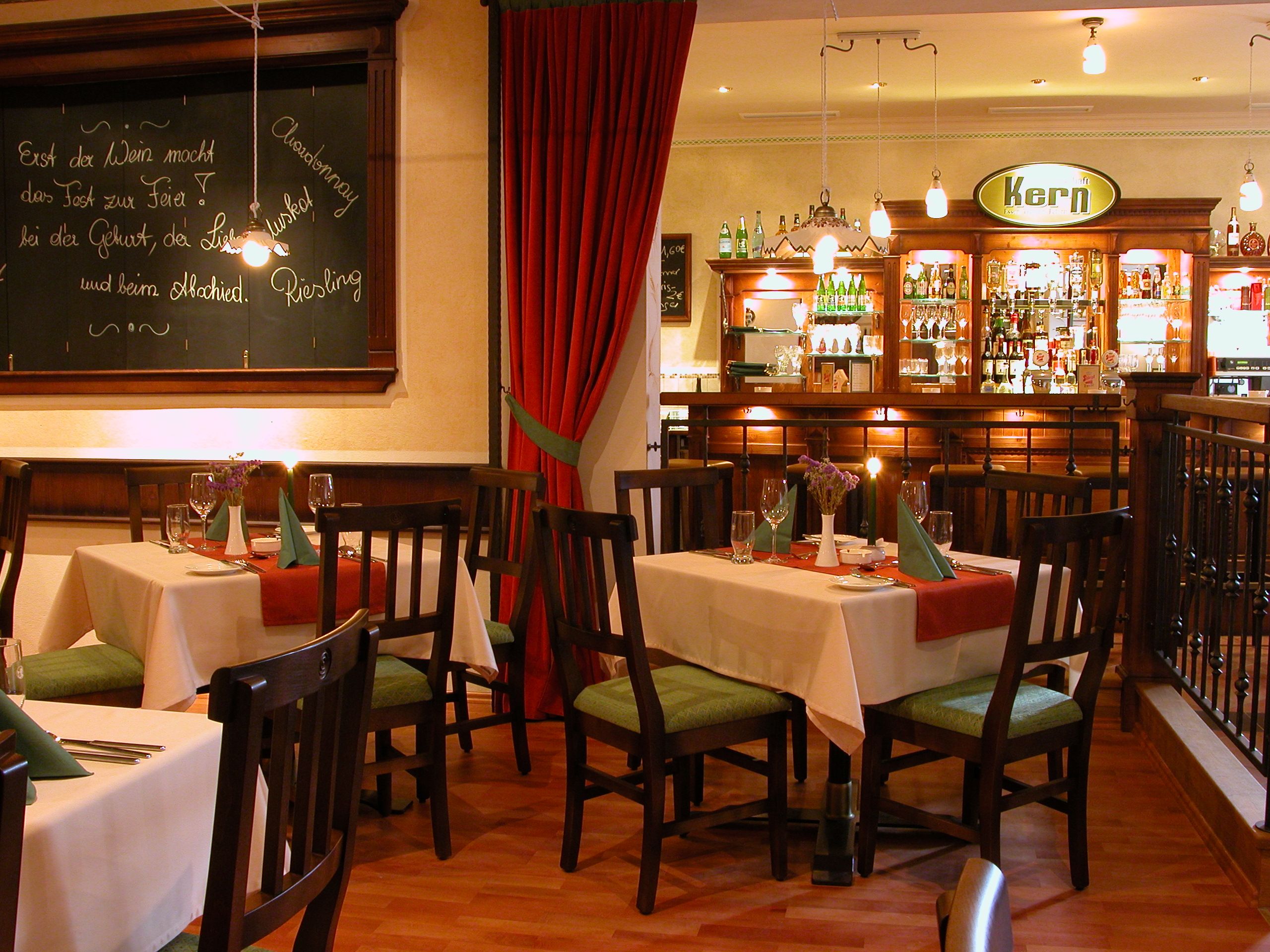 Gemütliches Restaurant mit Holzmöbeln, gedeckten Tischen und einer Bar im Hintergrund.