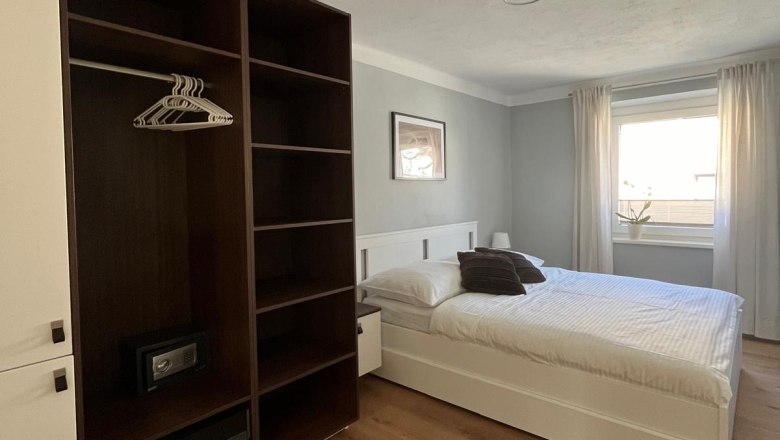 Modernes Schlafzimmer mit Doppelbett, Kleiderschrank und Fenster mit Vorh&auml;ngen.