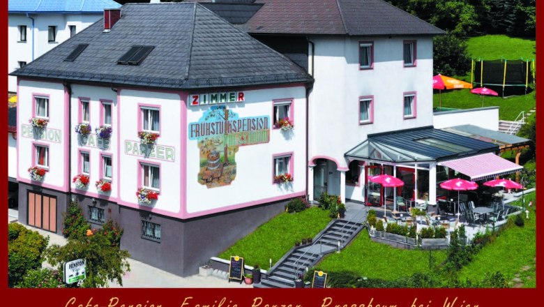 Außenansicht der Cafe-Pension Parzer mit Terrasse und Sonnenschirmen.