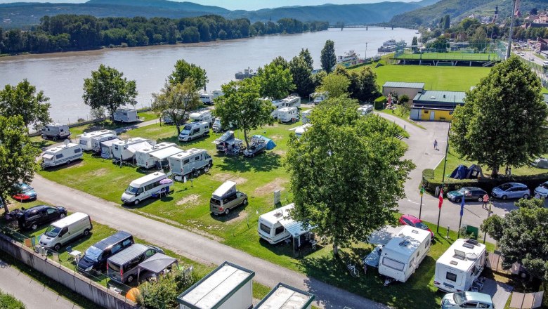 Luftaufnahme eines Campingplatzes am Fluss mit Wohnmobilen und Zelten.