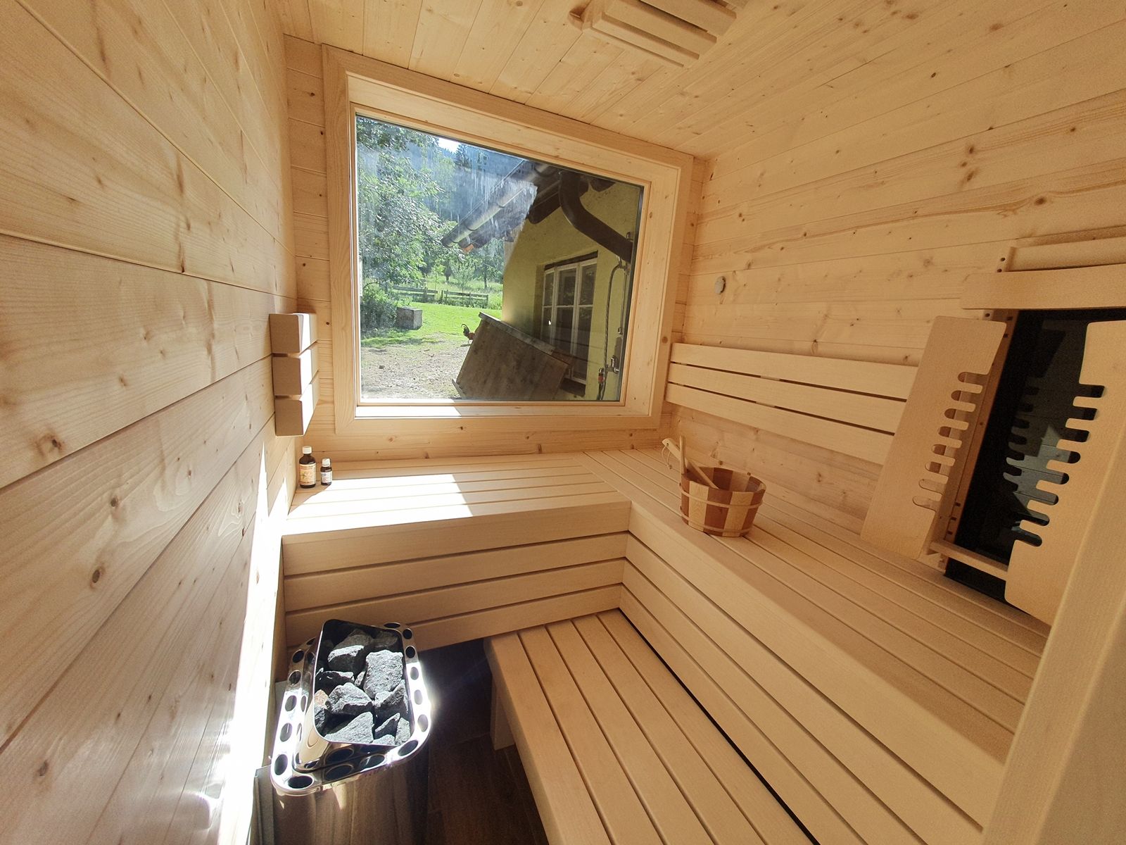 Innenansicht einer modernen Sauna mit Holzverkleidung und großem Fenster.