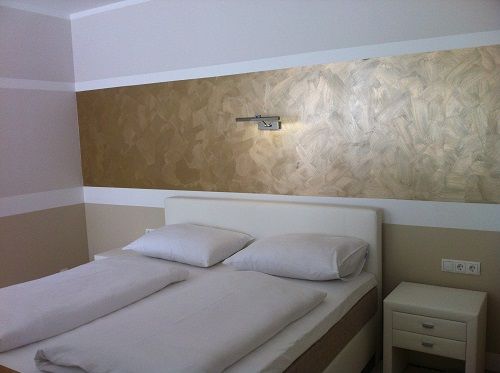 Modernes Schlafzimmer mit Doppelbett und goldener Wanddekoration.