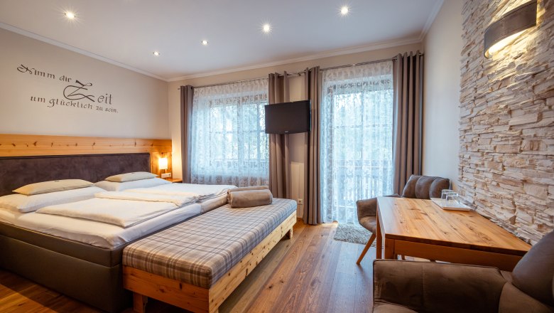 Gem&uuml;tliches Schlafzimmer mit Doppelbett, Holzm&ouml;beln und Steinwand.