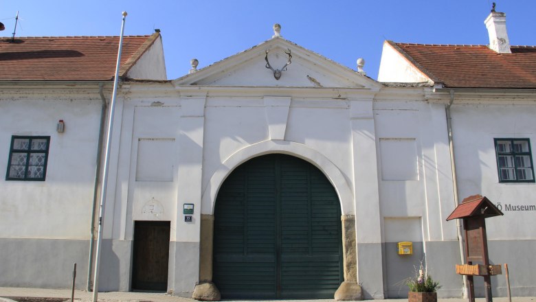 Historisches Geb&auml;ude mit gro&szlig;em Tor und Hirschgeweih an der Fassade.