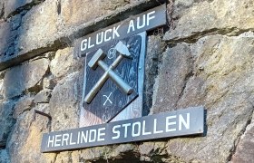 Eingang zum Herlinde Stollen mit Bergbauzeichen und Schriftzug 'Gl&uuml;ck Auf'.