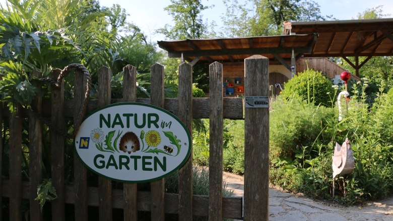 Eingang zu einem Garten mit einem Schild 'Natur im Garten'.