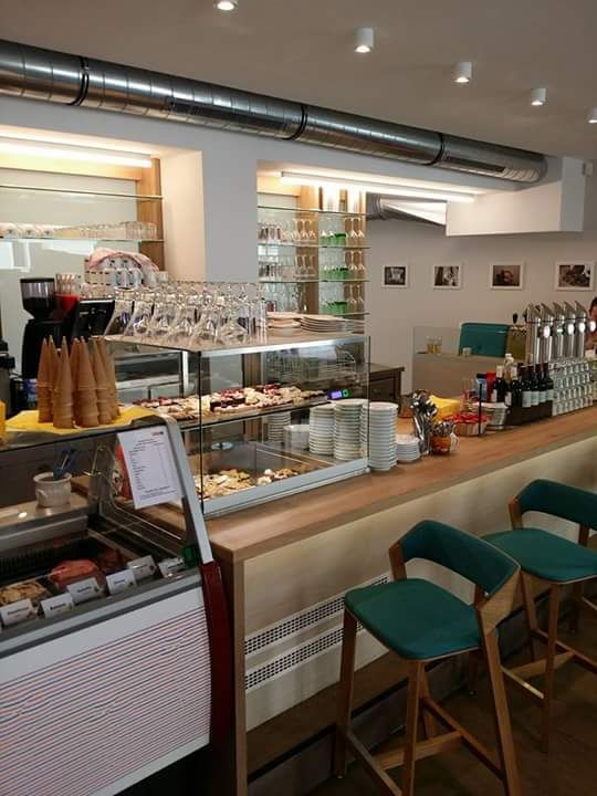 Innenansicht eines Cafés mit Theke, Barhockern und einer Vitrine mit Snacks.