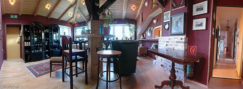 Gemütlicher Clubraum mit Holzmöbeln, Teppich und Bildern an den Wänden.