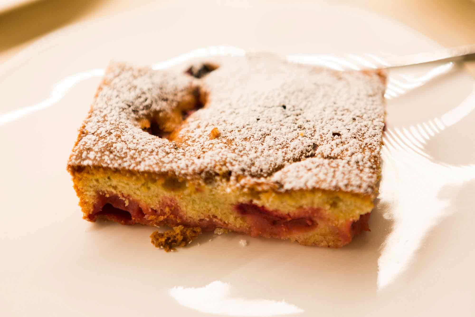Ein Stück hausgemachter Kuchen mit Puderzucker bestäubt auf einem Teller.