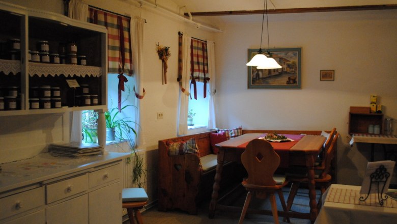 Gem&uuml;tliche K&uuml;che mit Holzm&ouml;beln und karierten Vorh&auml;ngen.