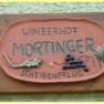 Schild mit der Aufschrift 'Winzerhof Mörtinger Scheibenpflug' und Verzierungen von Trauben und einer Eidechse.