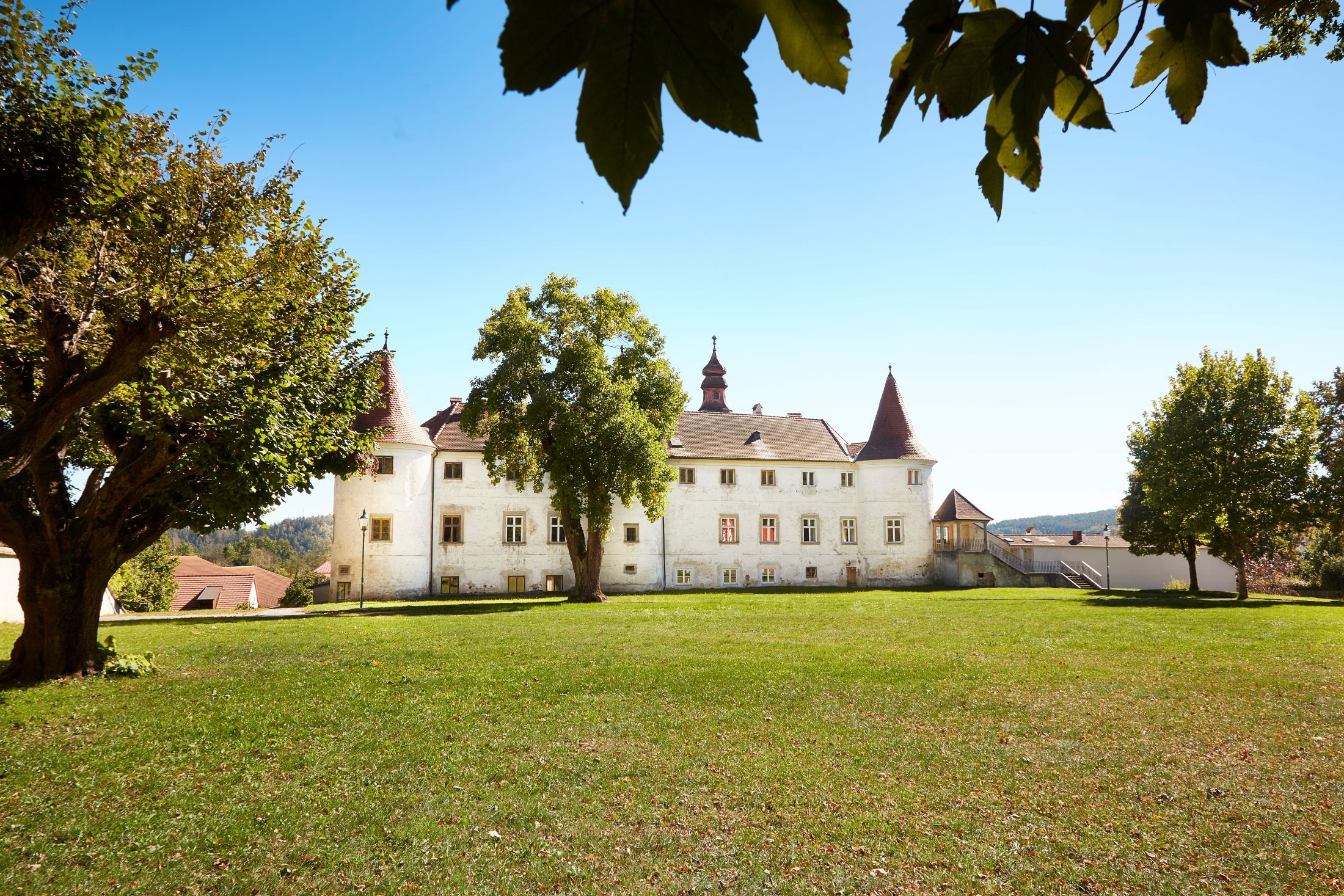 Schloss Dobersberg mit grüner Wiese im Vordergrund und Bäumen im Hintergrund.