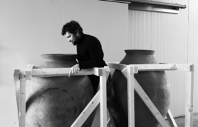 Person neben großen Tonamphoren in einem Weinkeller.