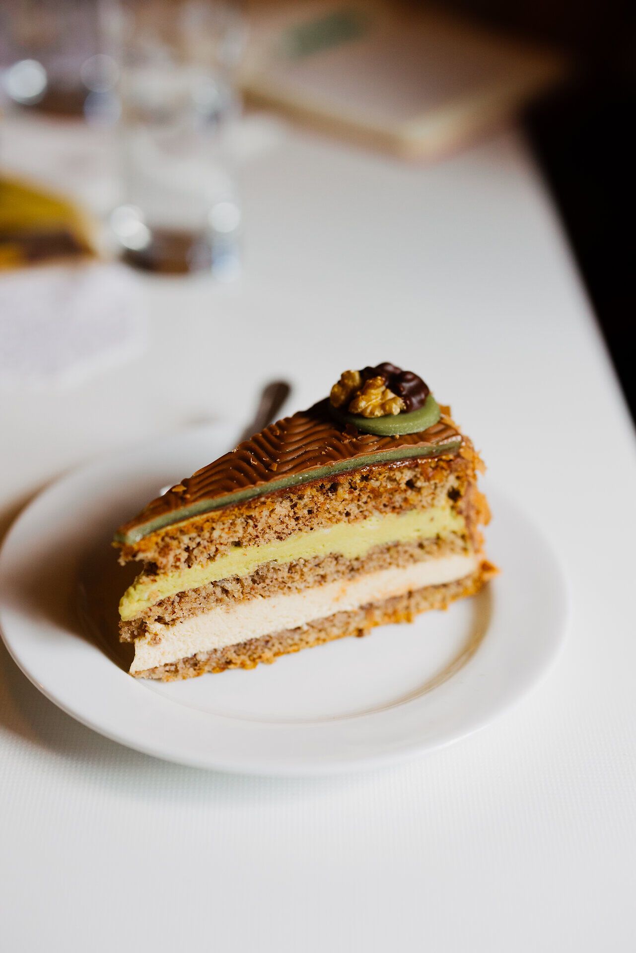Die Ghega-Torte verführt mit ihrer zarten Schicht aus Pistazien und Nussnougat, die harmonisch aufeinander abgestimmt sind. Ein Genuss, der die Sinne betört und zum Verweilen einlädt, während man die süße Köstlichkeit in der charmanten Atmosphäre der Konditorei genießt.