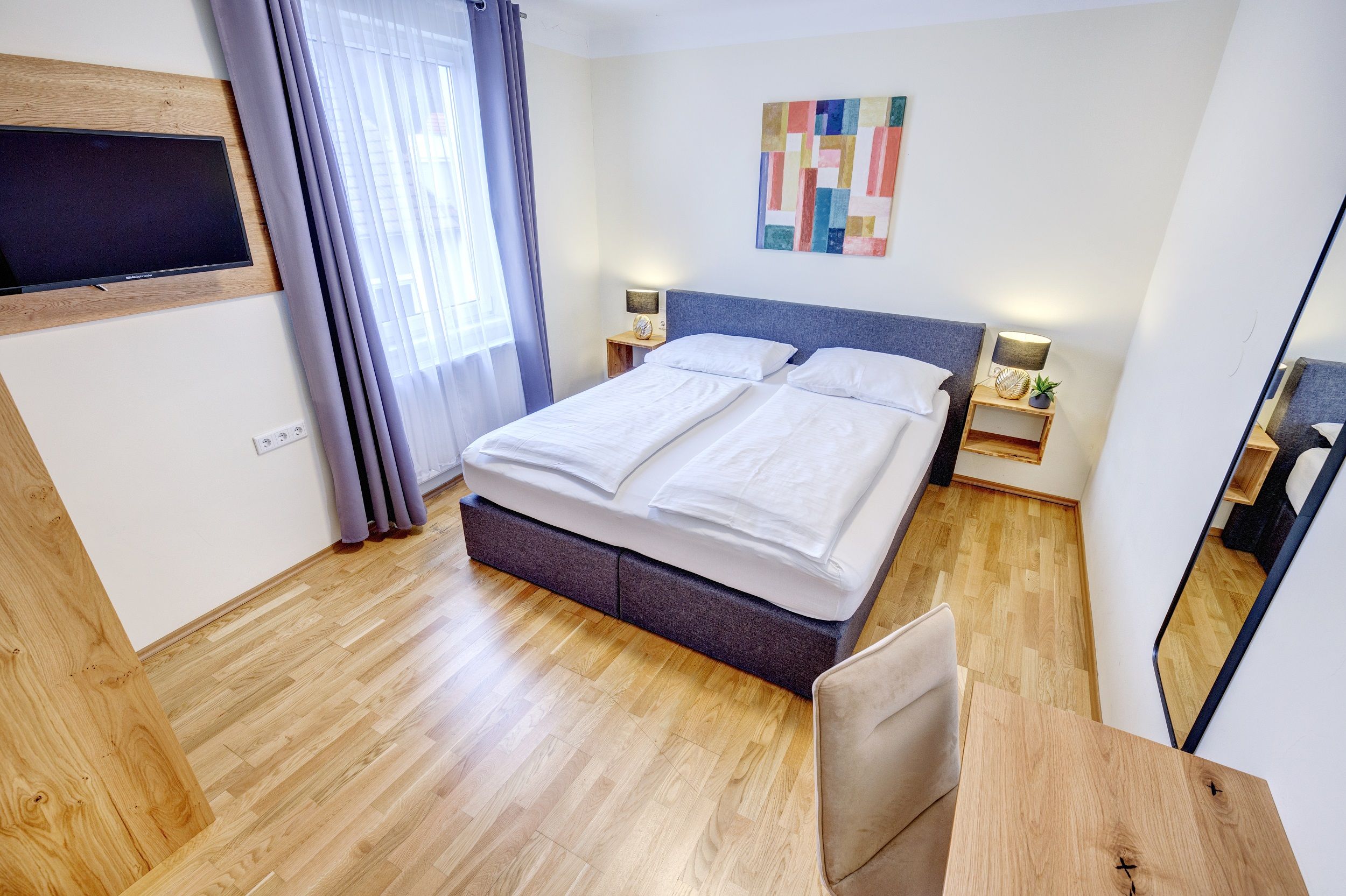 Doppelzimmer mit großem Fenster und Holzfußboden 