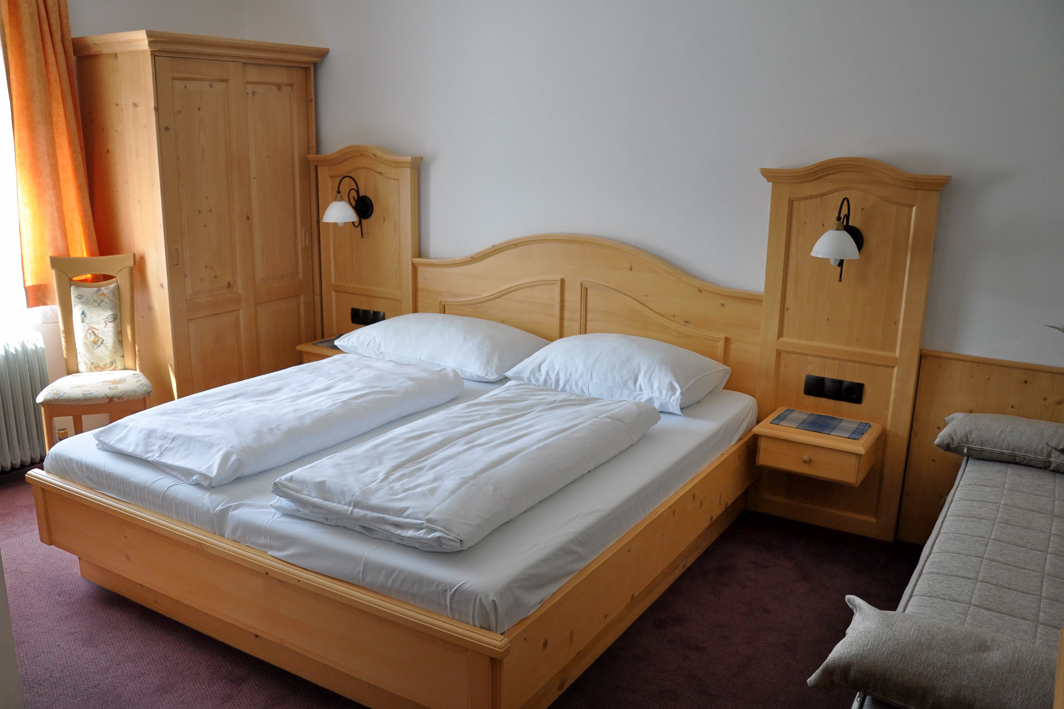 Komfortzimmer mit Doppelbett und Vollholzmöbeln.