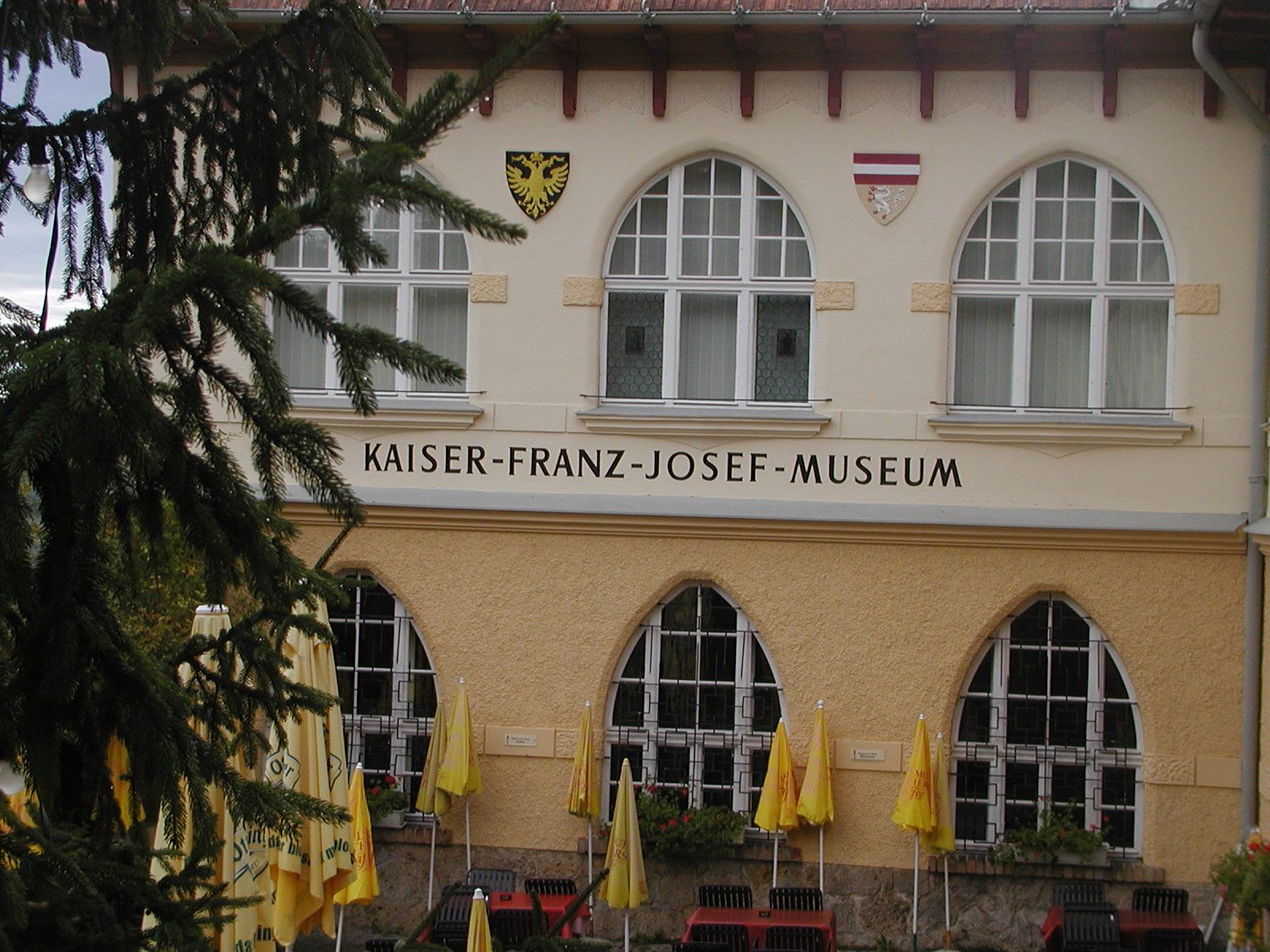 Fassade des Kaiser-Franz-Josef-Museums mit Fenstern und Wappen.
