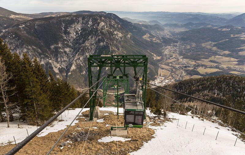 Die Raxseilbahn schwebt majestätisch über die schneebedeckten Hänge, während die atemberaubende Berglandschaft sich unter ihr entfaltet. Hier, wo die frische Bergluft und die Ruhe der Natur aufeinandertreffen, wird jeder Moment zu einem unvergesslichen Erlebnis. Genießen Sie die spektakulären Ausblicke und die unberührte Schönheit der Alpen.