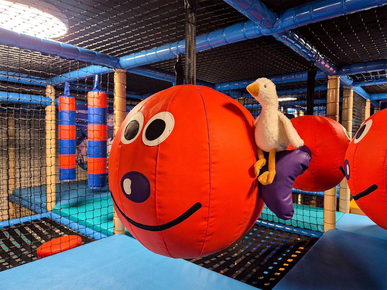 Spielbereich mit großen roten Kugeln und einem Plüschtier in einem Indoor-Spielplatz.