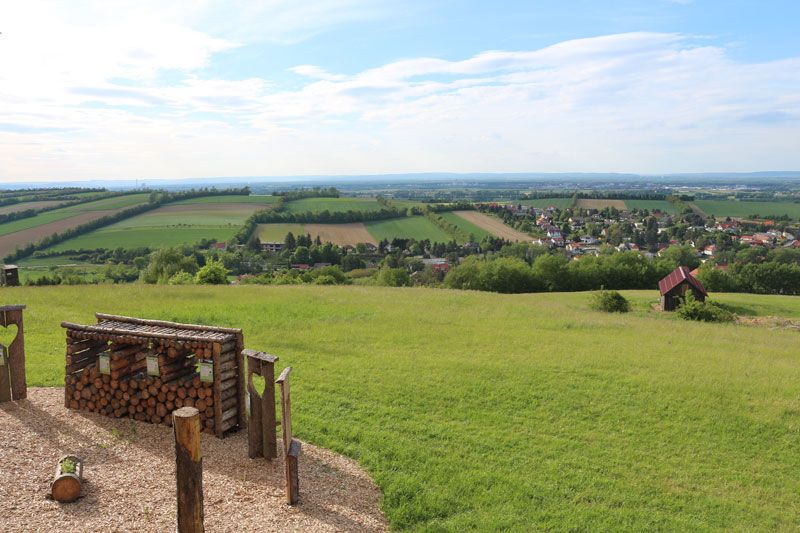 Aussicht vom Balkon Tullnerfeld auf grüne Felder und ein Dorf.