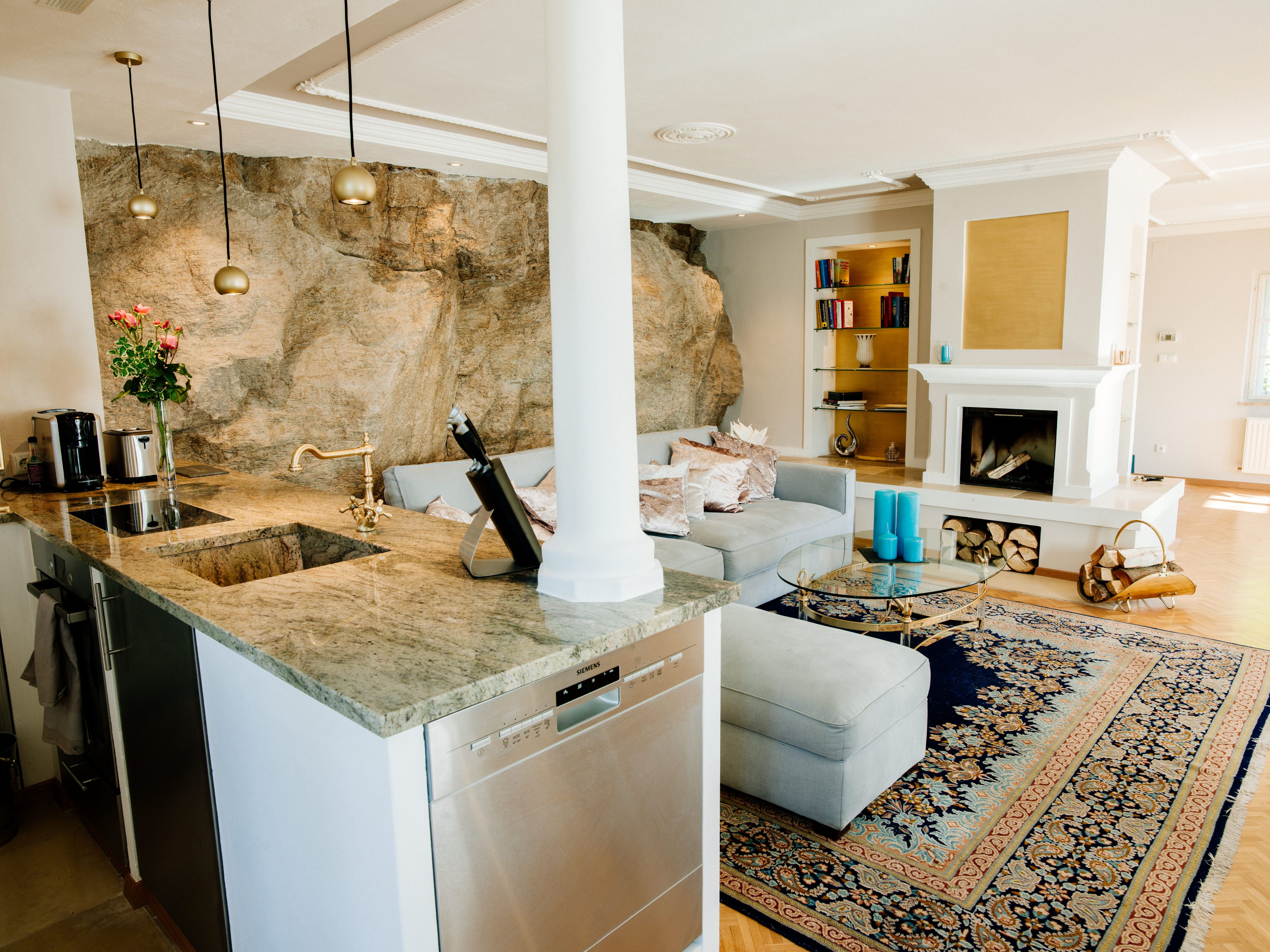 Elegantes Wohnzimmer mit Kamin, Teppich und offener Küche.