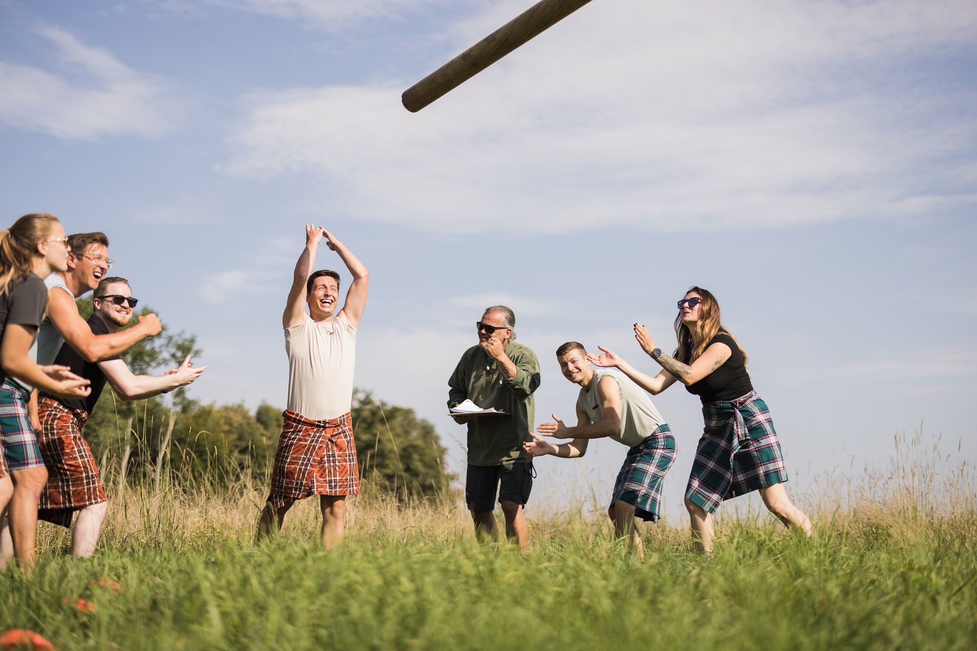 Gruppe von Menschen in Kilts bei den Highland Games auf einer Wiese.