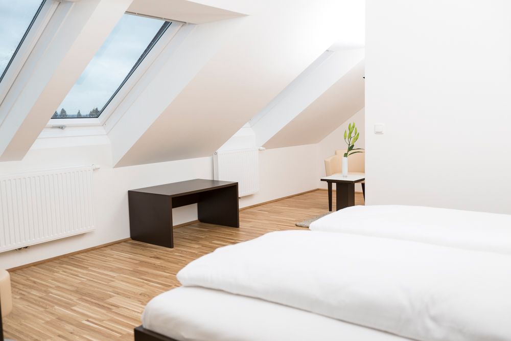 Modernes Gästezimmer mit Dachfenstern, Holzboden und minimalistischer Einrichtung.