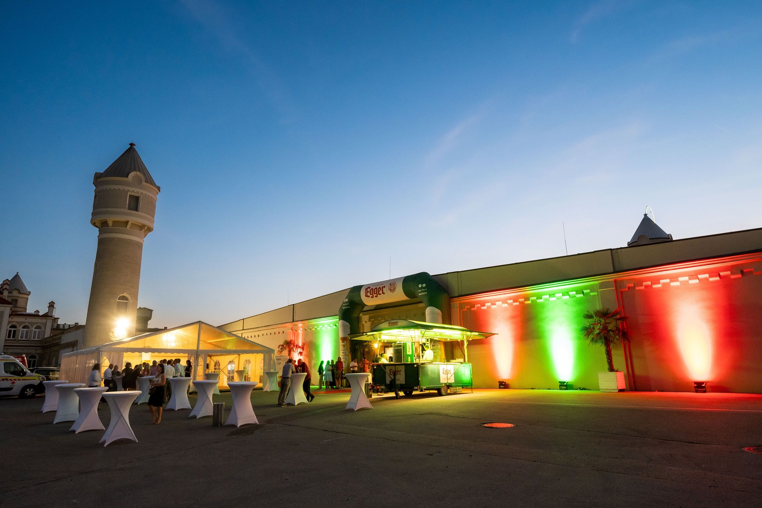 Abendveranstaltung im Freien mit beleuchtetem Gebäude und Zelten.