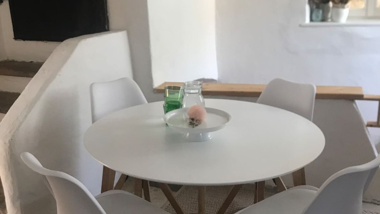 Moderne Sitzecke mit rundem Tisch und vier weißen Stühlen in einem hellen Raum.