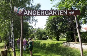 Eingang zu den Angerg&auml;rten mit Schild und Spazierg&auml;ngern.