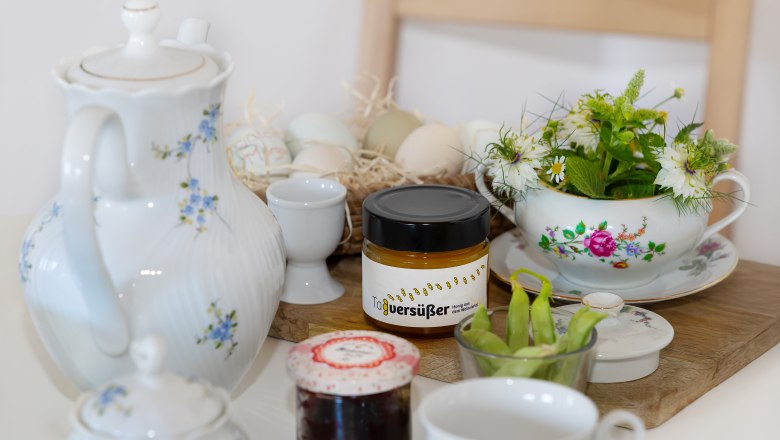 Ferienhaus Weinmeyer, © Josef Schimmer Frühstückstisch mit Teekanne, Honigglas, Marmelade, Eiern und Blumen.