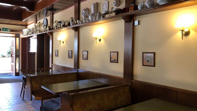 Innenansicht eines traditionellen Gasthauses mit Holzm&ouml;beln und Dekorationen auf einem Regal.