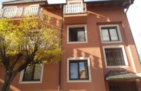 Au&szlig;enansicht eines dreist&ouml;ckigen Hauses mit orangefarbener Fassade und wei&szlig;en Fensterrahmen.