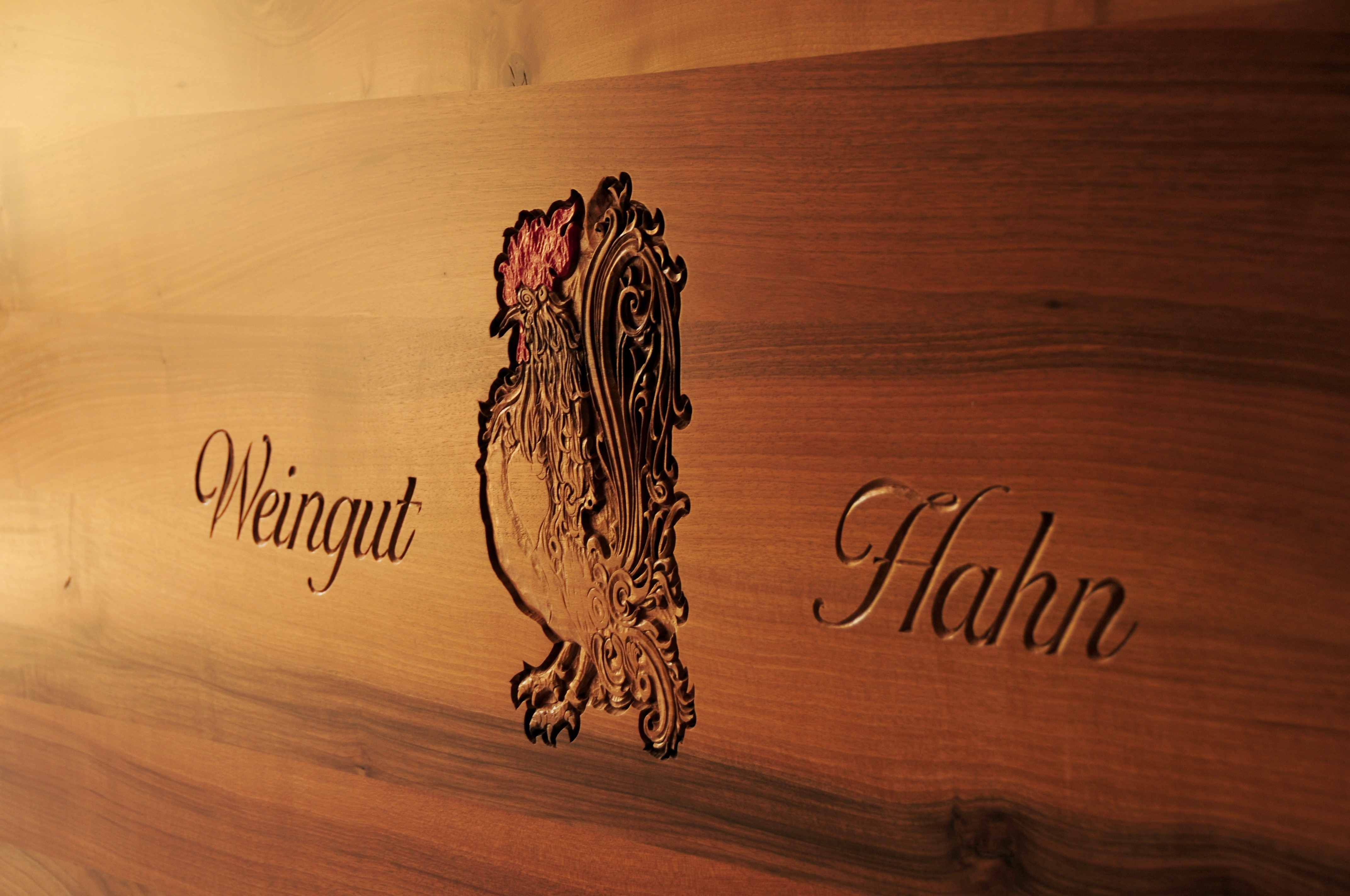 Holztafel mit eingraviertem Hahn und Schriftzug 'Weingut Hahn'.
