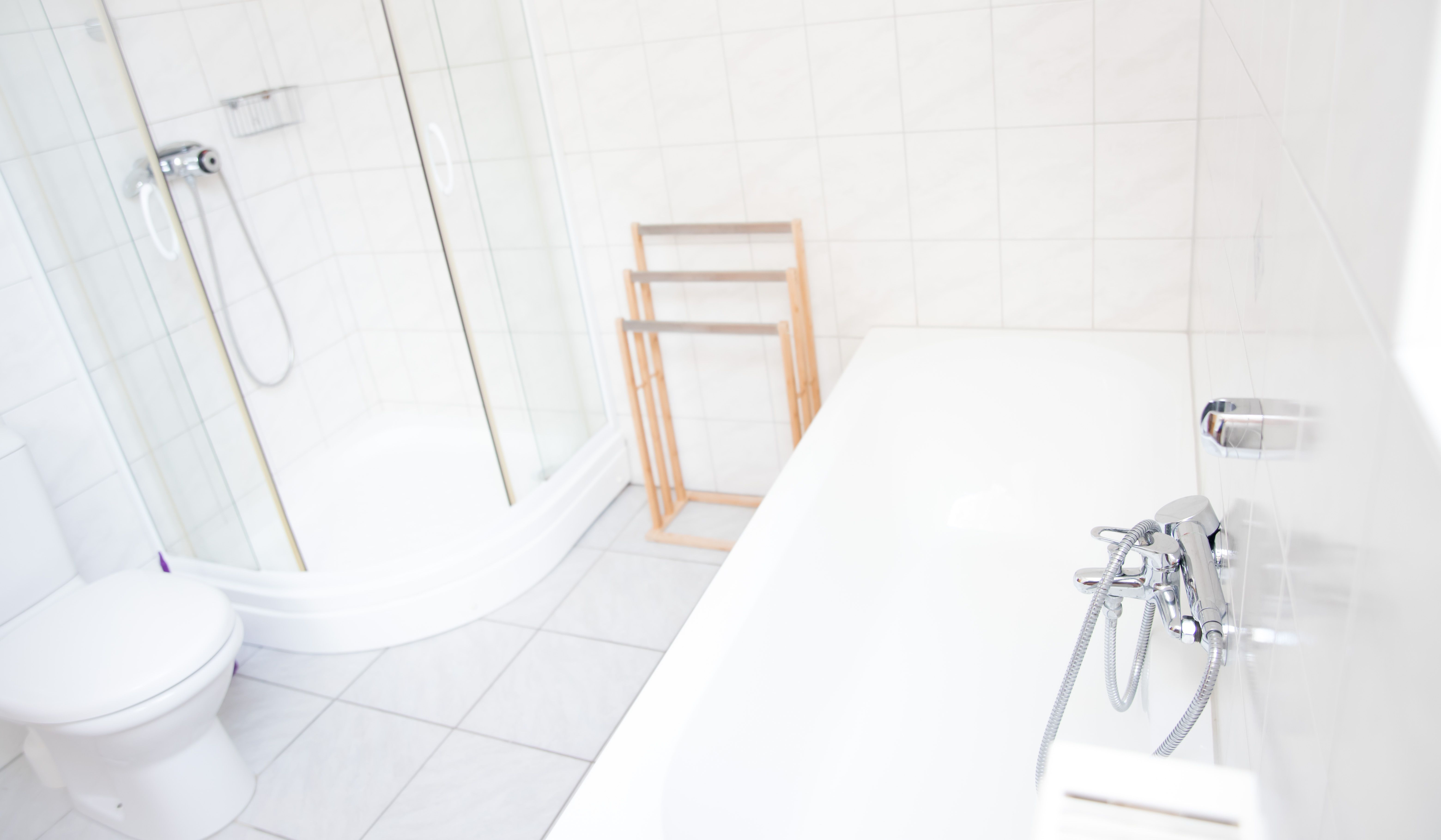 Helles Badezimmer mit Dusche, Badewanne und Handtuchhalter.