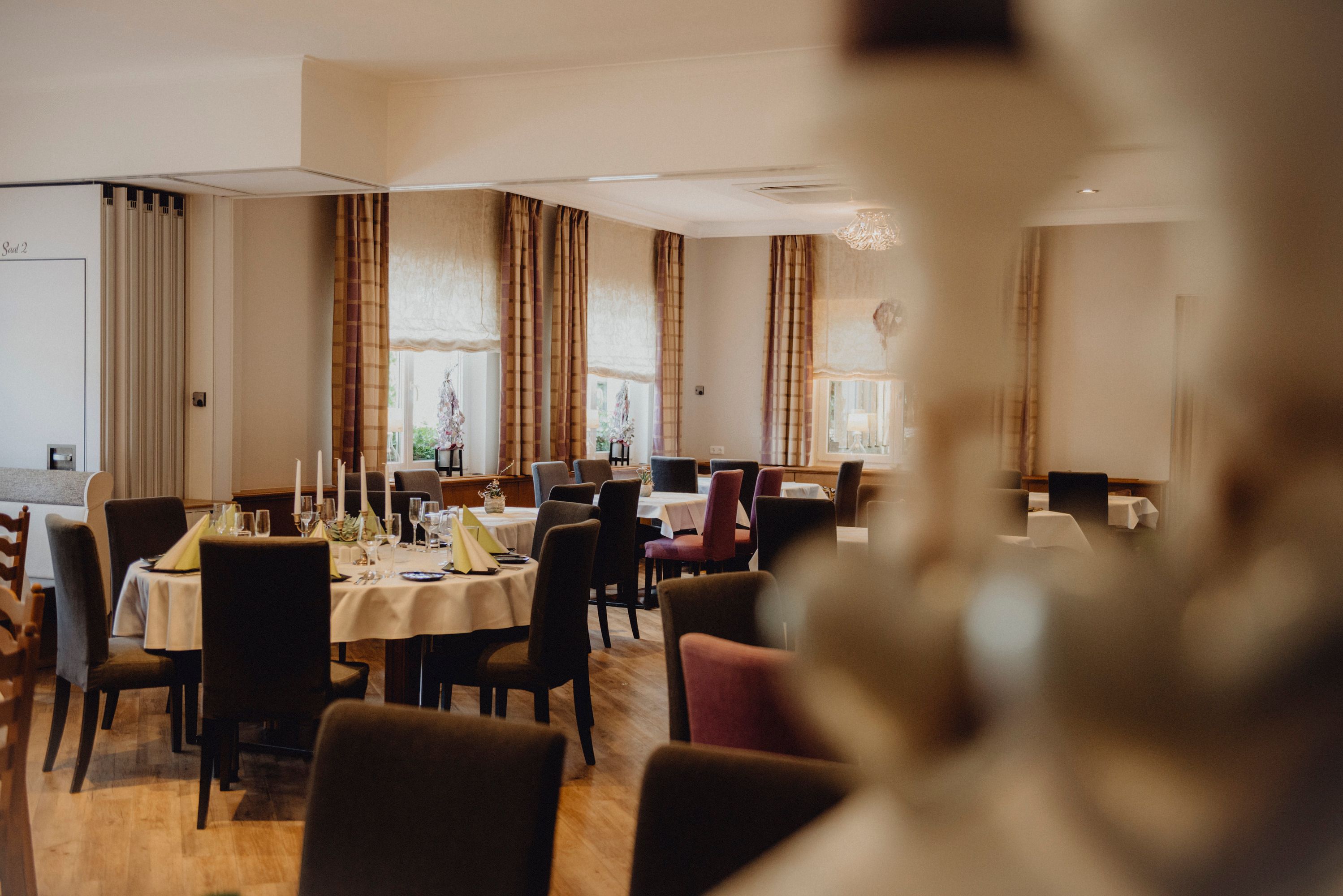 Eleganter Speisesaal mit gedeckten Tischen und Kerzen.