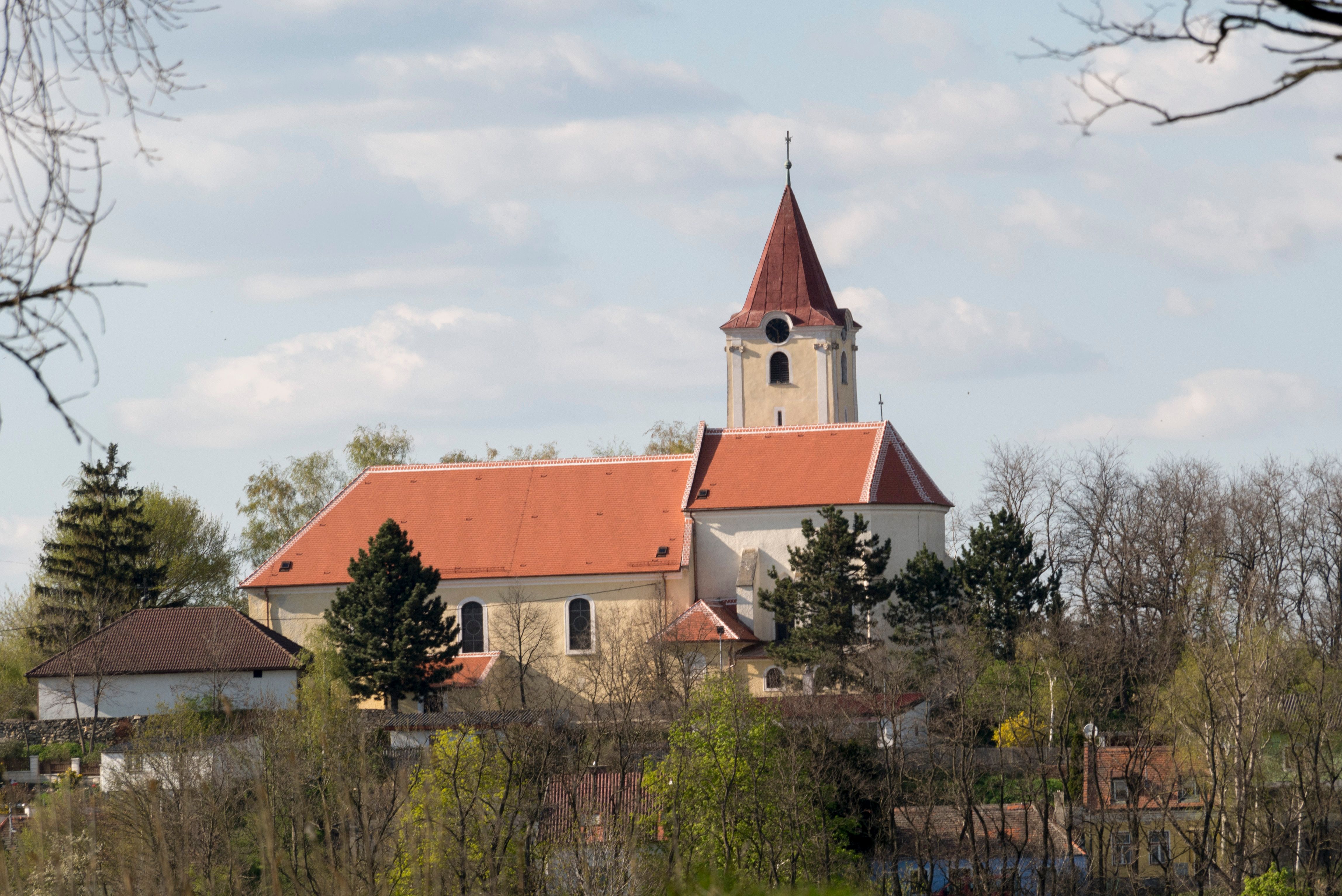 Kirche St. Georg in Pfaffendorf mit rotem Dach und Turm, umgeben von Bäumen.