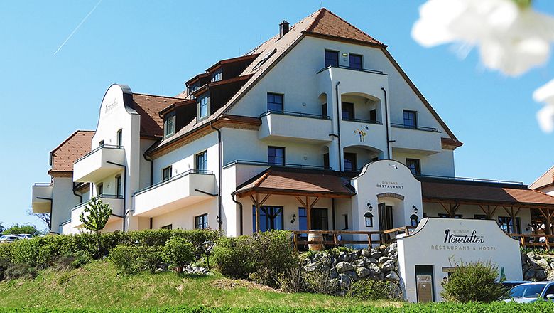Außenansicht eines großen, mehrstöckigen Gebäudes mit Balkonen und einem Restaurant im Erdgeschoss.